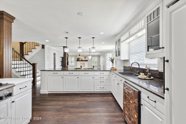 kitchen featuring pendant lighting, dark wood-type flooring, white cabinetry, sink, and kitchen peninsula