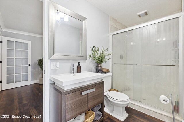 bathroom featuring toilet, a shower with door, wood-type flooring, ornamental molding, and vanity