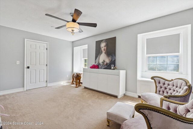 living area with light carpet and ceiling fan