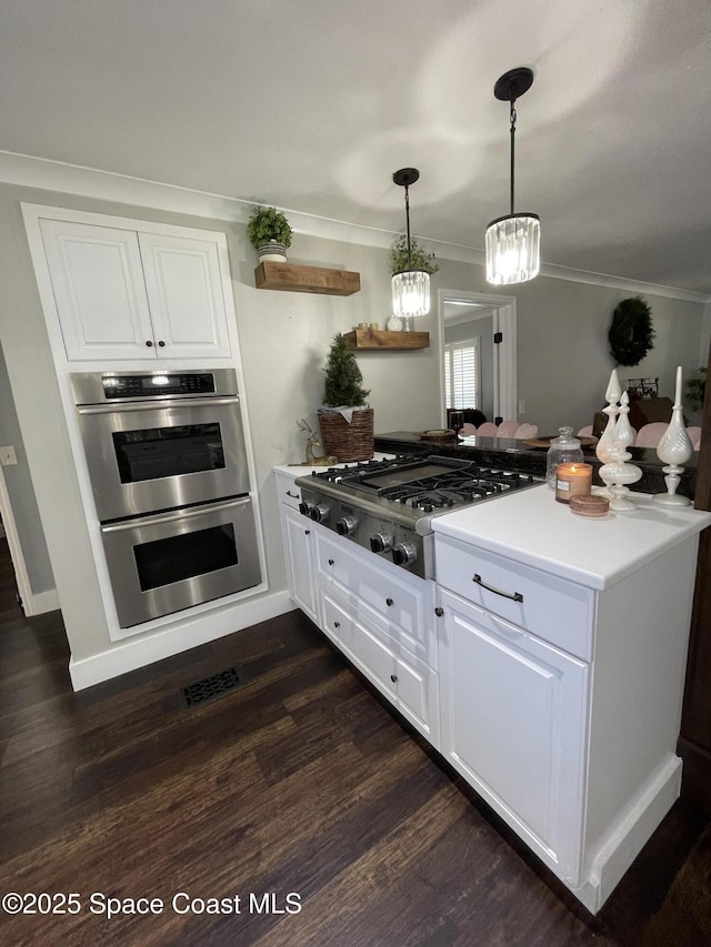 kitchen featuring stainless steel double oven, white cabinets, dark hardwood / wood-style flooring, hanging light fixtures, and gas cooktop