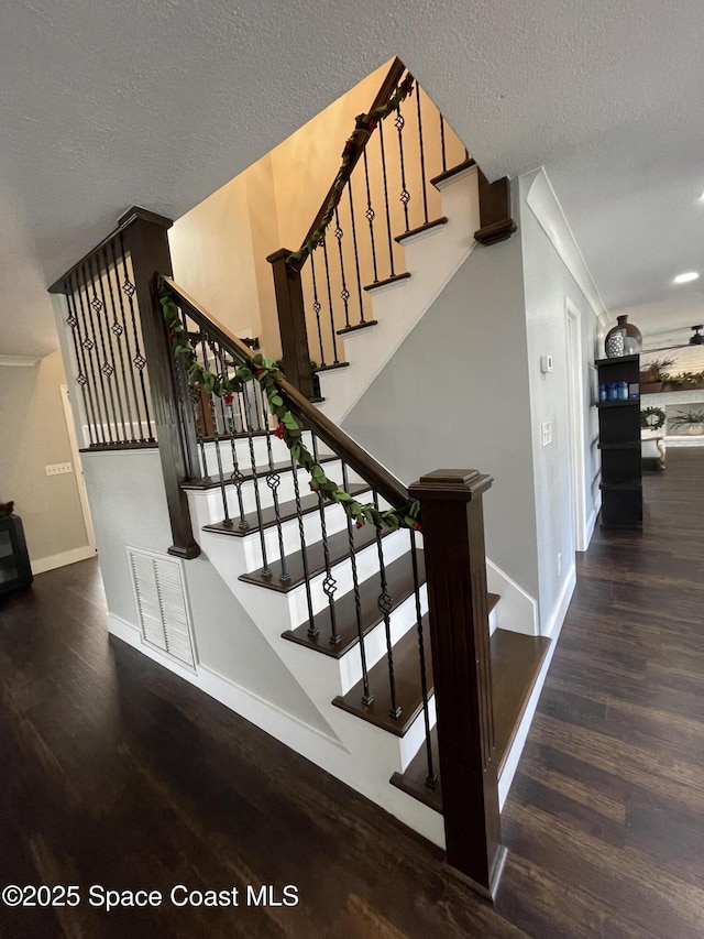 stairs with hardwood / wood-style floors and a textured ceiling