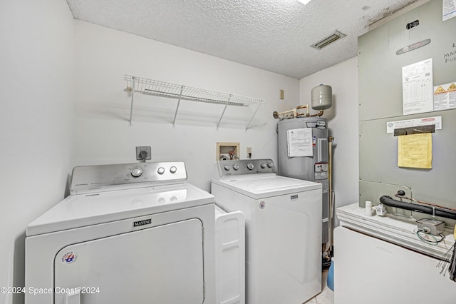 laundry area featuring water heater, visible vents, a textured ceiling, laundry area, and independent washer and dryer