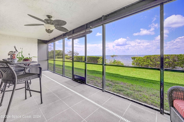 sunroom / solarium featuring a water view and a ceiling fan