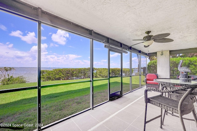 sunroom featuring a water view and ceiling fan