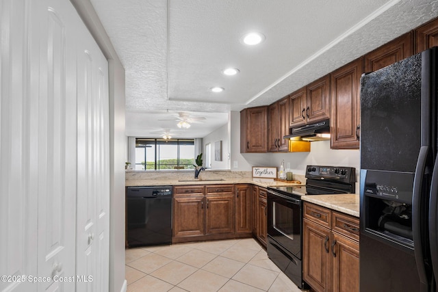 kitchen featuring under cabinet range hood, a textured ceiling, black appliances, a sink, and light tile patterned flooring