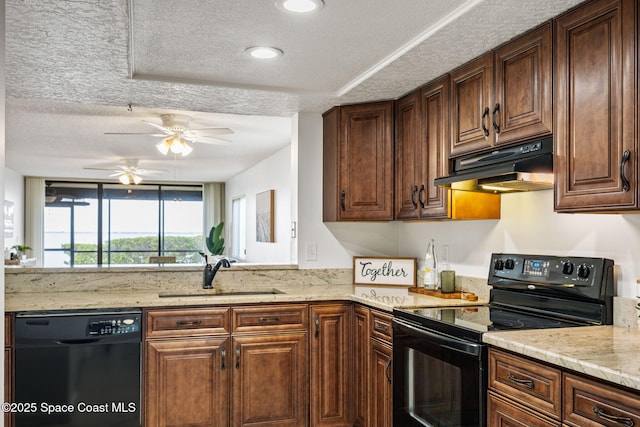 kitchen with light stone counters, under cabinet range hood, a textured ceiling, black appliances, and a sink