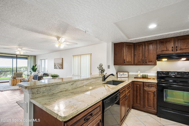 kitchen featuring a sink, a peninsula, light stone countertops, under cabinet range hood, and black appliances