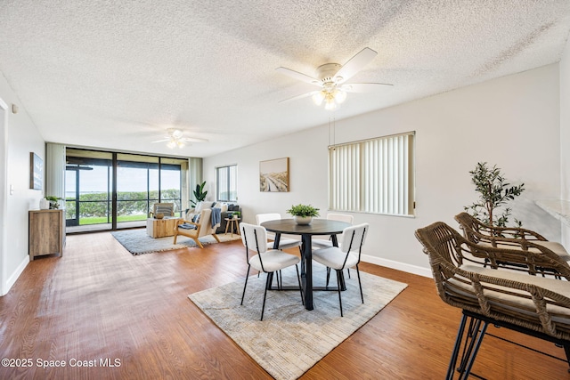 dining space featuring ceiling fan, a textured ceiling, baseboards, and wood finished floors