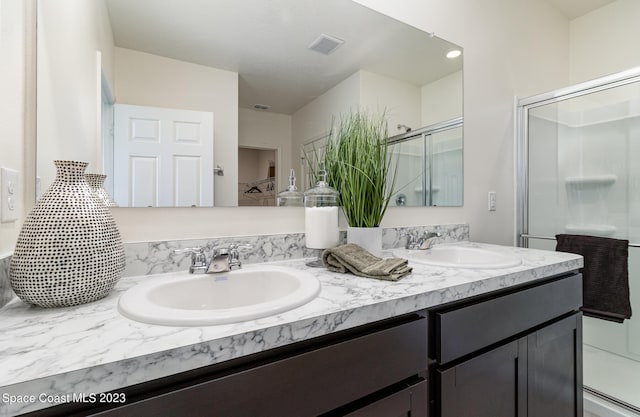 bathroom with an enclosed shower and dual bowl vanity