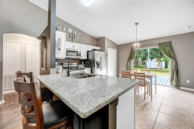 kitchen featuring pendant lighting, a textured ceiling, white cabinetry, kitchen peninsula, and appliances with stainless steel finishes