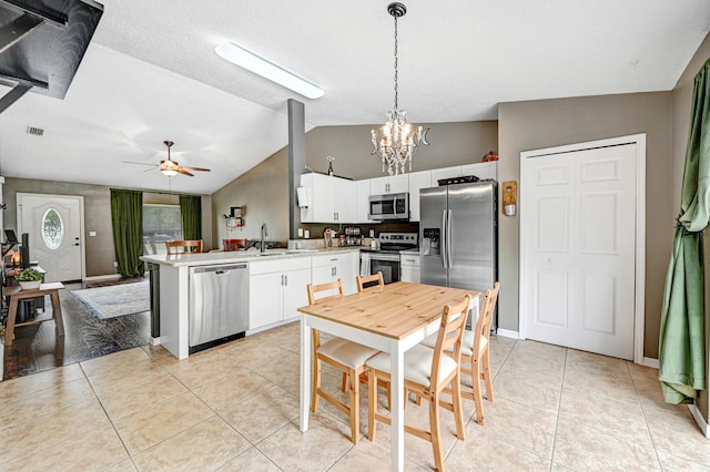 kitchen featuring white cabinets, hanging light fixtures, appliances with stainless steel finishes, ceiling fan with notable chandelier, and vaulted ceiling