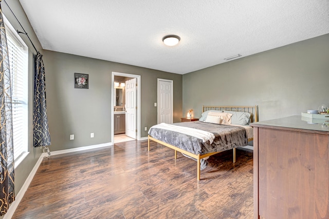 bedroom featuring ensuite bath, a textured ceiling, and dark hardwood / wood-style floors