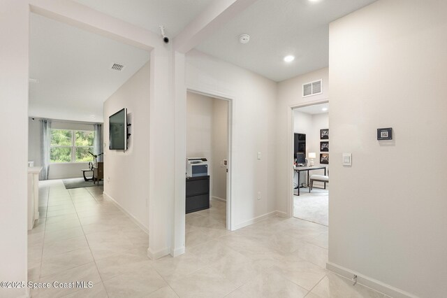 hall featuring light tile patterned floors and beam ceiling