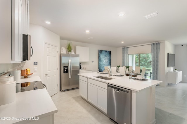 kitchen with stainless steel appliances, a kitchen island with sink, sink, and white cabinets