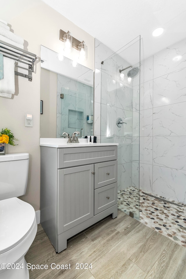 bathroom featuring toilet, hardwood / wood-style floors, a shower with door, and vanity