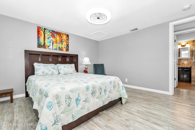 bedroom featuring light hardwood / wood-style flooring and ensuite bath