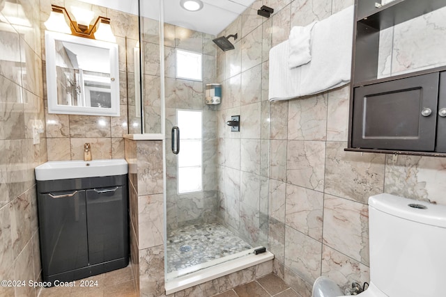 bathroom featuring a shower with shower door, vanity, tile patterned floors, and tile walls