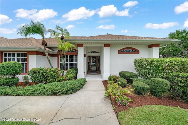 entrance to property featuring a shingled roof and stucco siding