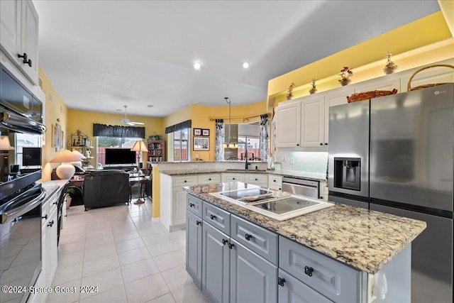 kitchen featuring stainless steel appliances, white cabinetry, open floor plan, a center island, and decorative light fixtures