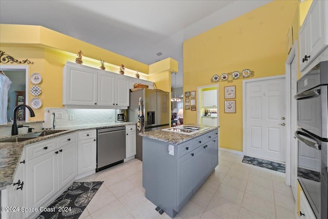 kitchen featuring backsplash, a center island, light tile patterned floors, stainless steel appliances, and white cabinets