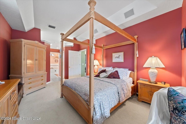 bedroom featuring light carpet, ensuite bath, lofted ceiling, and visible vents