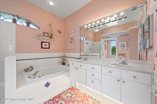 bathroom with a relaxing tiled tub, tile patterned flooring, and vanity