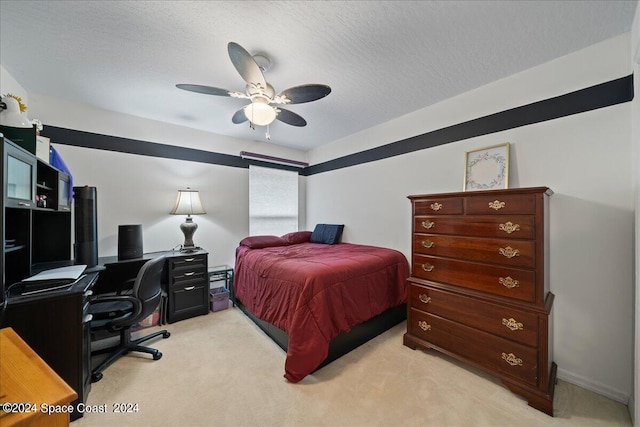 bedroom featuring ceiling fan, light carpet, and a textured ceiling