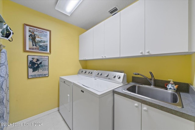 clothes washing area featuring sink, light tile patterned floors, cabinets, and washer and dryer