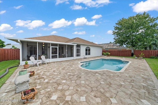 view of swimming pool with a sunroom and a patio area