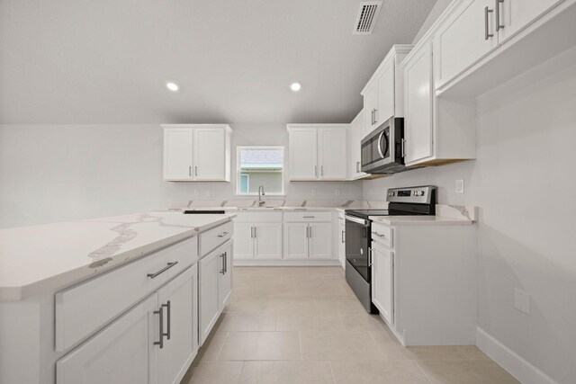 kitchen with light tile patterned floors, stainless steel appliances, white cabinetry, and sink