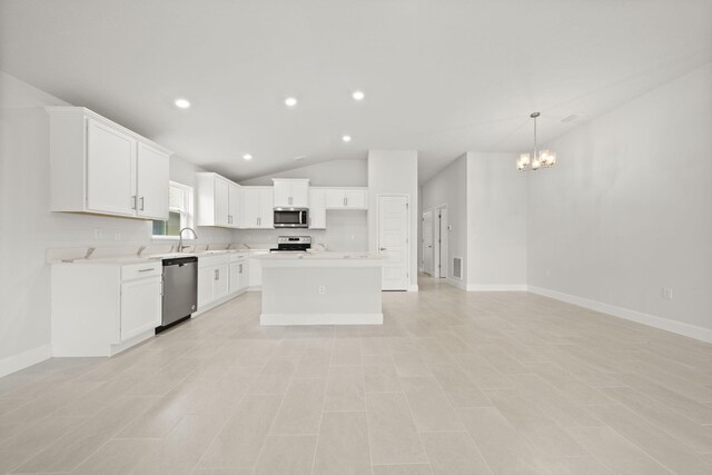 kitchen featuring appliances with stainless steel finishes, a notable chandelier, white cabinets, a kitchen island, and lofted ceiling