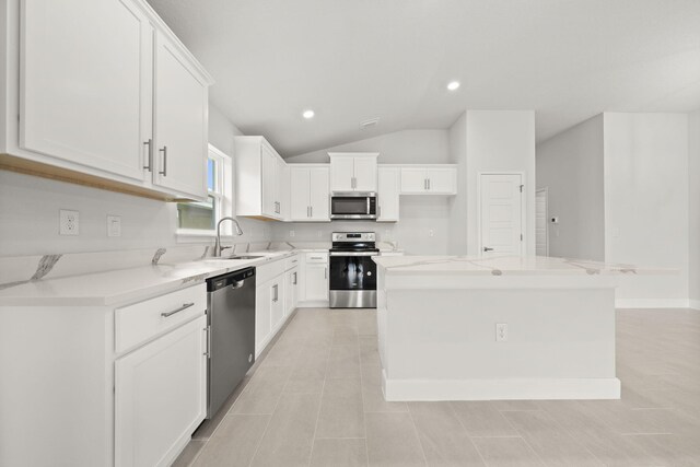 kitchen with a center island, white cabinets, sink, vaulted ceiling, and stainless steel appliances