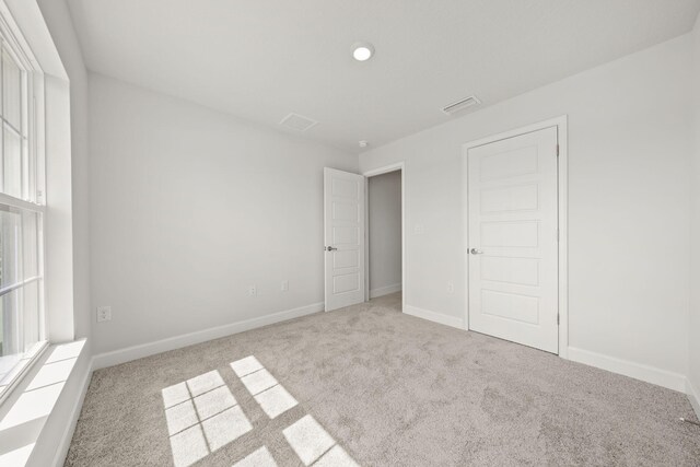 unfurnished bedroom with light carpet and a closet