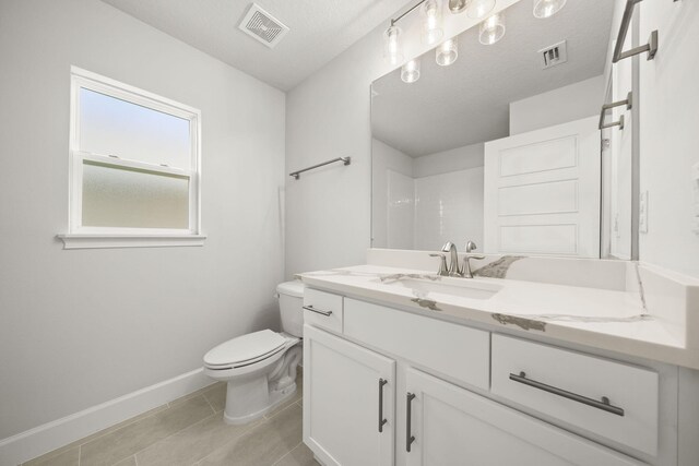 bathroom with walk in shower, a textured ceiling, vanity, tile patterned flooring, and toilet