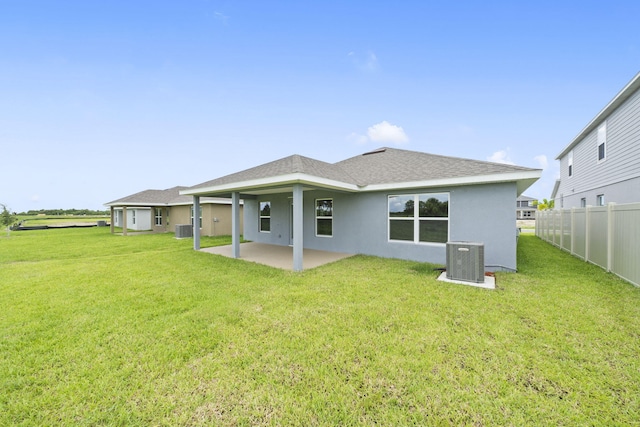 rear view of property featuring a patio area, a yard, and central AC