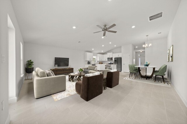 living room with ceiling fan with notable chandelier, vaulted ceiling, and light tile patterned flooring