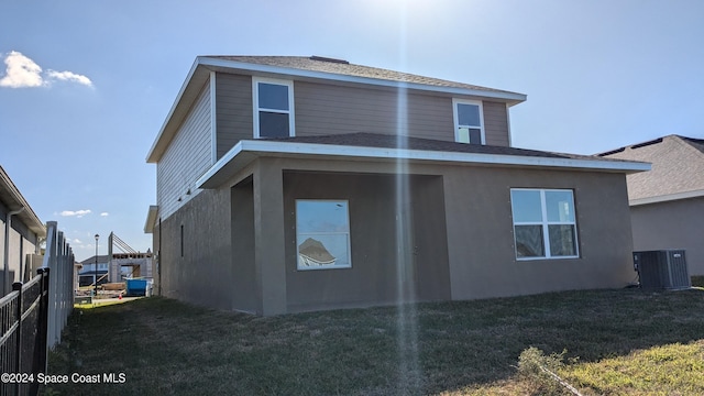 back of property featuring central air condition unit and a lawn