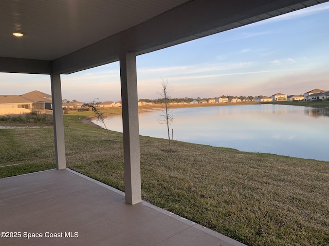 patio terrace at dusk with a water view and a lawn