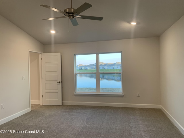 unfurnished room with lofted ceiling, carpet, ceiling fan, and a water view