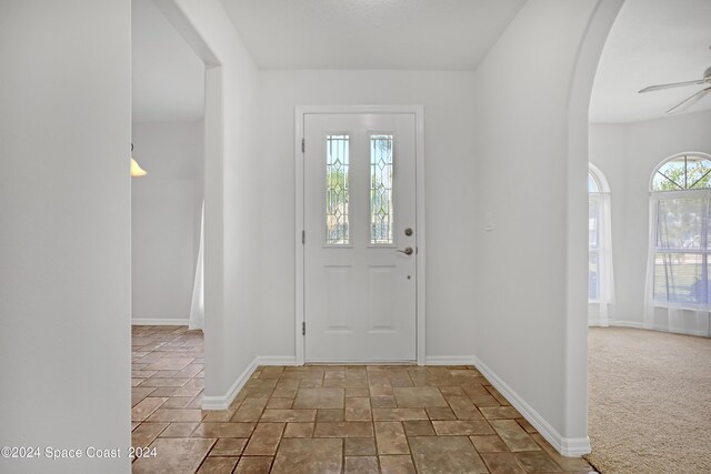 carpeted foyer entrance featuring ceiling fan