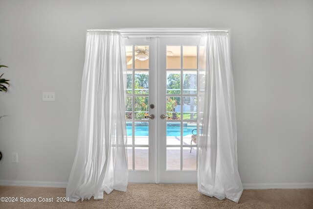 doorway to outside with a healthy amount of sunlight, light carpet, and french doors