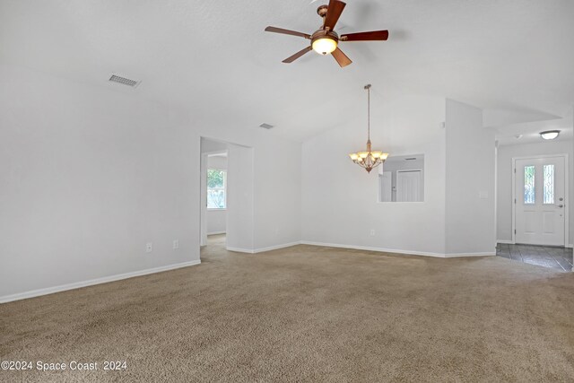 carpeted empty room featuring ceiling fan with notable chandelier and lofted ceiling