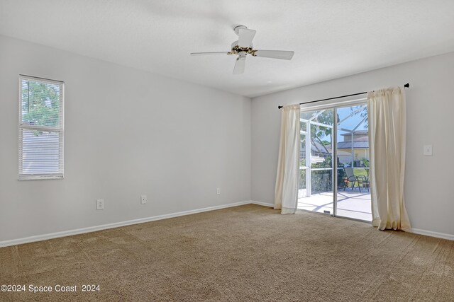 empty room with plenty of natural light, ceiling fan, and carpet