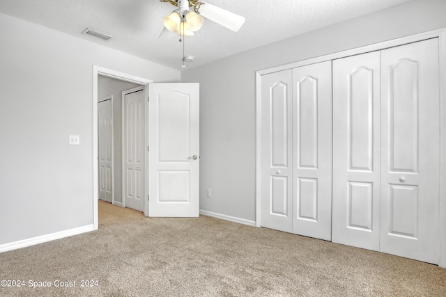 unfurnished bedroom featuring a textured ceiling, ceiling fan, and light carpet