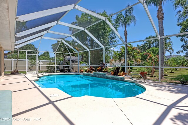 view of pool featuring glass enclosure, an outdoor structure, and a patio area