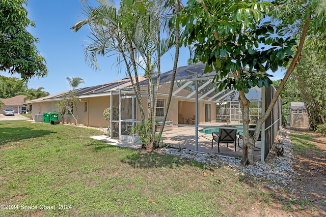 back of house with a patio area, a lawn, cooling unit, a storage shed, and glass enclosure