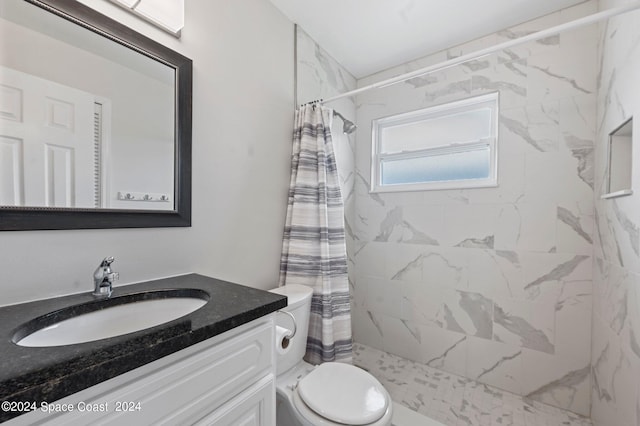 full bathroom featuring toilet, a tile shower, and vanity