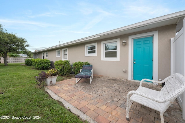 rear view of house with a patio, a yard, and stucco siding