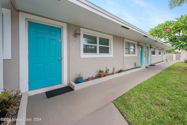 property entrance with a lawn and stucco siding