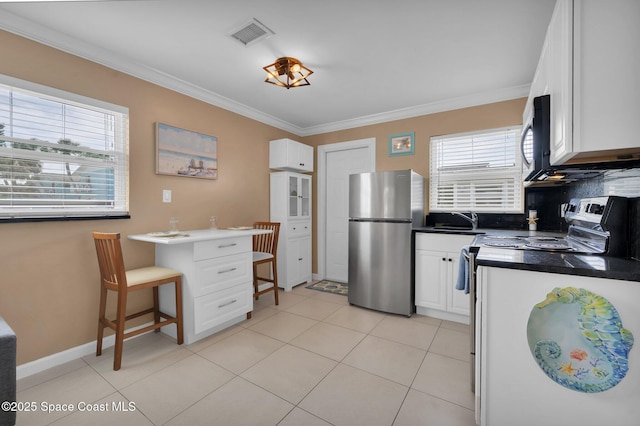 kitchen featuring range with electric cooktop, a healthy amount of sunlight, white cabinets, ornamental molding, and freestanding refrigerator